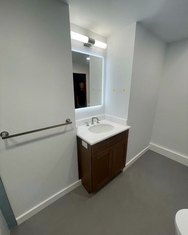 Bathroom with wood vanity and backlit mirror