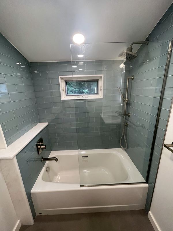 Blue-gray glass tile tub surround with glass panel