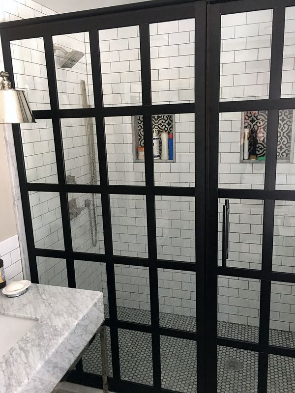 Black grid shower door with patterned tile