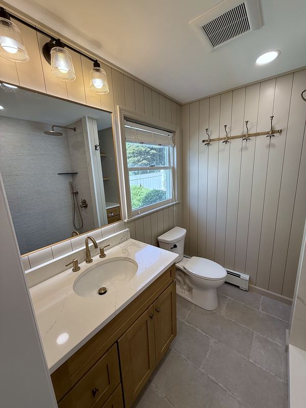 Bathroom with wood vanity, shiplap walls and black light fixture