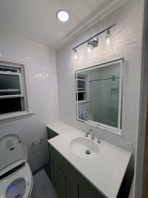 White vanity with quartz top and white tile walls