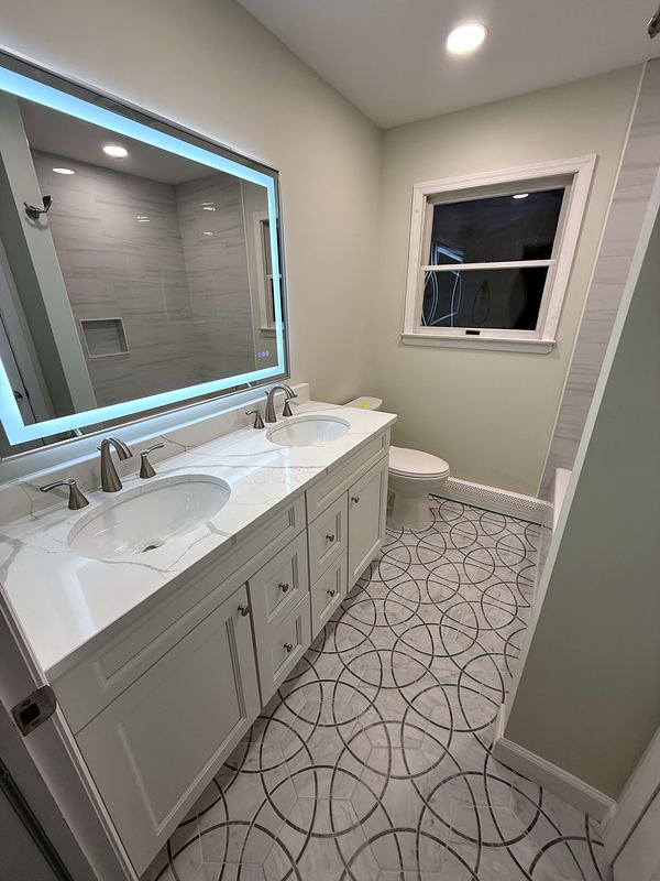 Double vanity with backlit mirror and patterned floor tile
