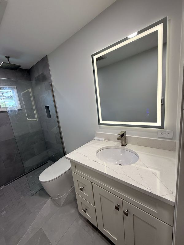 Backlit mirror vanity with walk-in gray tile shower