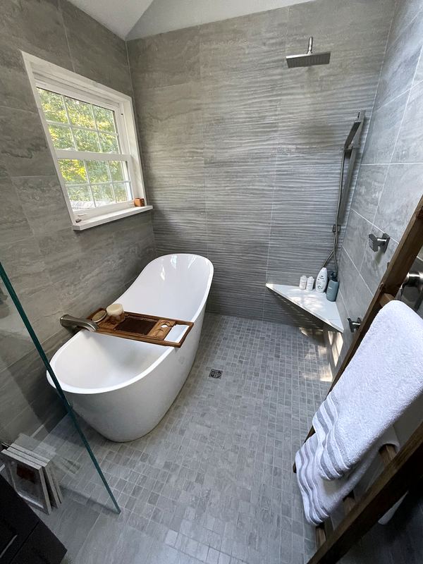 Freestanding soaking tub with gray wood-look tile