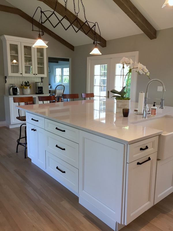 White kitchen with large island, quartz top and vaulted beamed ceiling