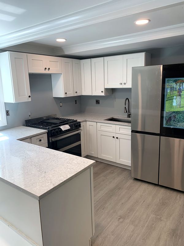 White shaker kitchen with quartz island and stainless appliances