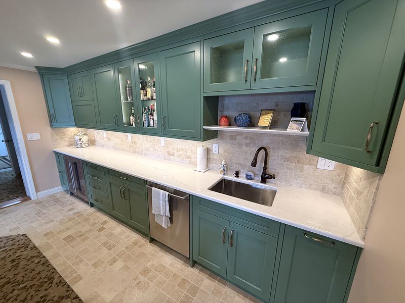 Green painted kitchen with glass-front uppers and quartz countertops
