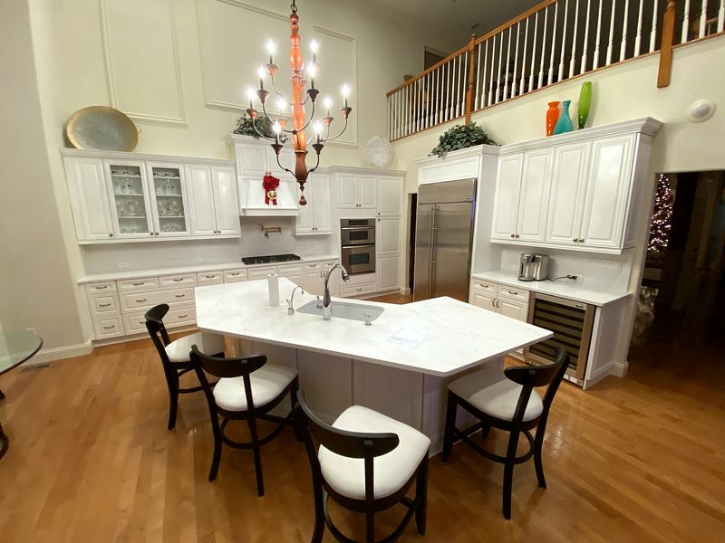 White kitchen with angled island under a chandelier
