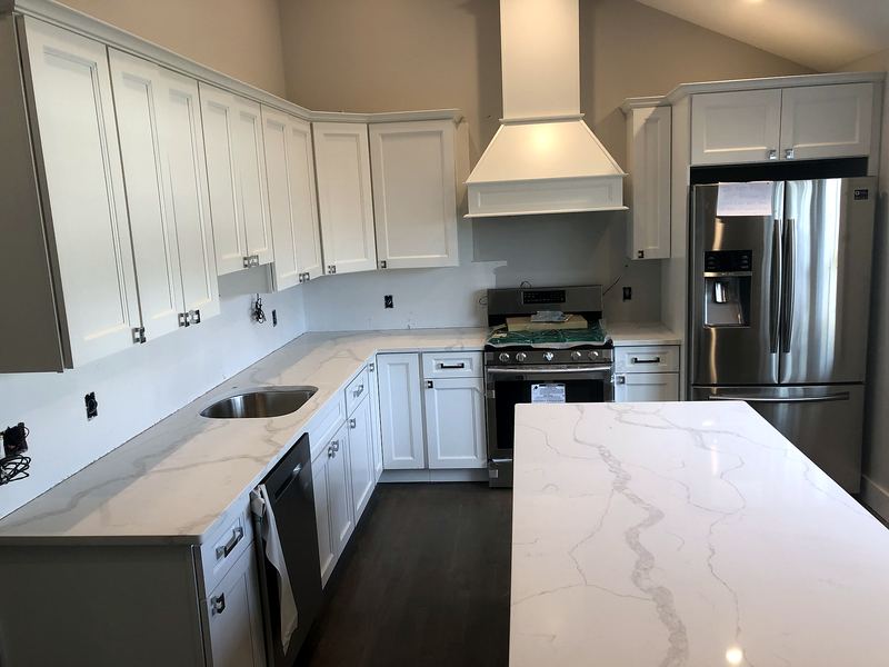 White kitchen with chimney hood and marble-look quartz island