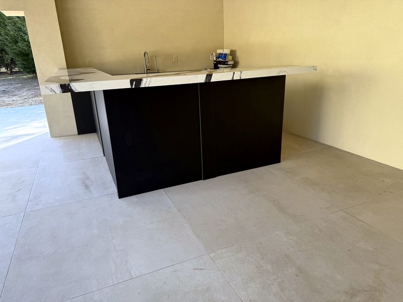 Outdoor kitchen bar with black cabinets and a white veined countertop